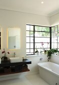 Free-standing bathtub and black floating washstand in bathroom