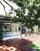 View across deck into open-plan living area with kitchen counter and dining area