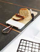 Bread and knife on chopping board on charcoal-grey kitchen worksurface