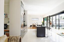 View past free-standing counter and fitted kitchen to summery terrace and dining area
