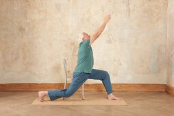 Krieger (Yoga), Schritt 1: Mit einer Gesäßhälfte sitzen, Bein nach hinten, Arme nach oben strecken