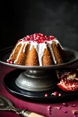 Pomegranate and rosewater cake with icing on a metal cake stand