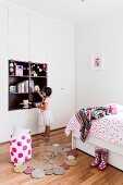 Children's room with bed and floor-to-ceiling wardrobe, girl in front of alcove