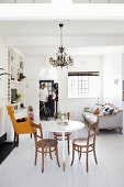 Chandelier, white shelving and vintage furniture in bright period apartment; man with bicycle in background