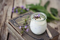 Ice cream parfait made from sage flowers in a glass on an old gardening book