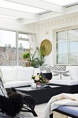 Black wicker coffee table and comfortable couch in conservatory extension with Scandinavian ambiance