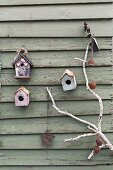 Weathered birdhouse on wooden wall with white branch decorated nostalgically