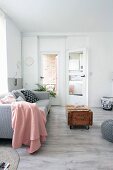 Pink blanket on pale grey couch behind vintage wooden crate used as coffee table