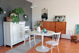 Round table and high chair in dining area with white vintage cabinet and retro sideboard