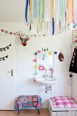 Bunte Geschenkbänder an Lampenschirm vor weißem Waschbecken in Mädchenzimmer