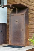 Rusted front door and porch on wood-clad façade