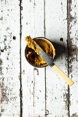 Masala-Knoblauch-Butter im Schälchen mit Messer (Draufsicht)