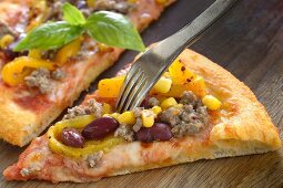 Mexican pizza with minced meat, beans and sweet corn (close-up)