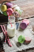 Colourful macaroons in a jar and next to a bottle of milk