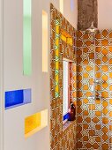 Vintage-style shower fitting on ornate wall tiles and stained-glass niches