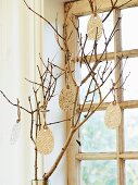 Paper Easter eggs hung from branch in front of window