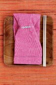 Pink linen napkin with name tag and chopsticks on wooden dish