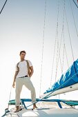 Junger Mann in Freizeitkleidung steht auf Segelboot