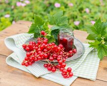 Redcurrants and a jar of redcurrant jam on a garden table