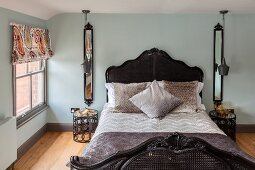 Nostalgisches Bett mit Korbgeflecht und symmetrisch angeordneten Nachttischen, Wandspiegel und Pendelleuchten