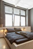 Reduziertes Schlafzimmer mit maßgefertigtem Doppelbett vor Fenster