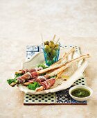 Pecorino breadsticks wrapped in ham with olives and pesto
