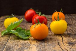 Orange, red and yellow tomatoes on a wooden surface