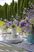 Blau-weiß gedeckter Gartentisch mit Blumensträußen