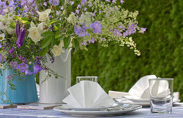 Vases of purple and white flowers on festively set garden table