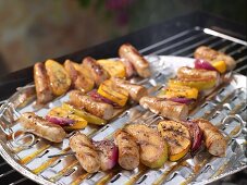 Colourful grilled sausage kebabs with onions and apples