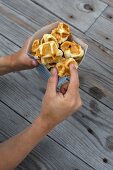 A hand holding a paper bag of waffle bites