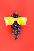 A bunch of red grapes wearing yellow sunglasses