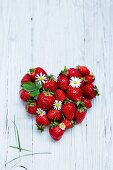 A heart made from fresh strawberries on a white wooden surface