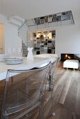 White dining table and plexiglas chairs in open-plan living area of architect-designed house