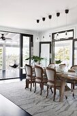 Rustic wooden table with upholstered chairs and pendant lamp in a bright dining area