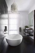 Elegant, free-standing bathtub in the bathroom with black floor