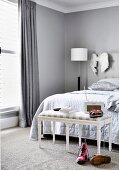 Upholstered bench in front of the bed in the bedroom in shades of gray