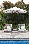 Two sun loungers under a white parasol by the pool