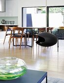 Suspended fireplace in front of dining table and wooden chairs