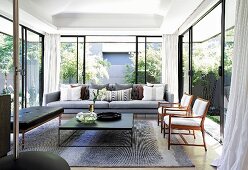 Living room with glass walls leading to summery garden