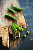 Pea pods on a rustic wooden surface