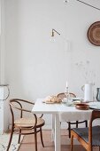 Set white dining table and wooden chairs below light-bulb lamp on wall