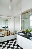 Books on edge of bathtub in bathroom with chequered floor