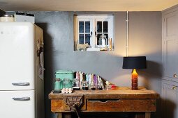 Old workbench in kitchen below small window in grey wall