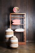 Shelving and floor vases against dark wood panelling on wall