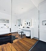 A modern white bathroom with a make-up table and a shower area with a glass panel