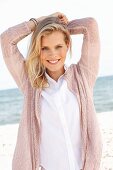 A young blonde woman wearing a white blouse and a dusty pink cardigan