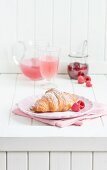 Breakfast with a croissant, raspberries, juice and raspberry jam