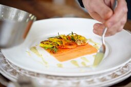 Plating up smoked salmon with walnut, shallots and edible flowers