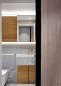 Marble-clad washstand with custom wooden base cabinets seen through half-open sliding door